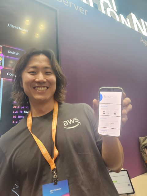 An Annapurna Labs team member holds up a phone displaying Loka's BEVFusion presentation at the AWS Summit New York booth.